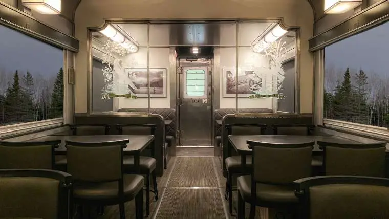 Voiture restaurant intérieure de train VIA Rail avec sièges confortables et vue panoramique.